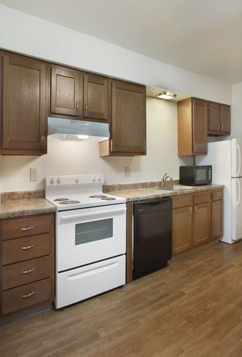 an empty kitchen with white appliances and wooden cabinets