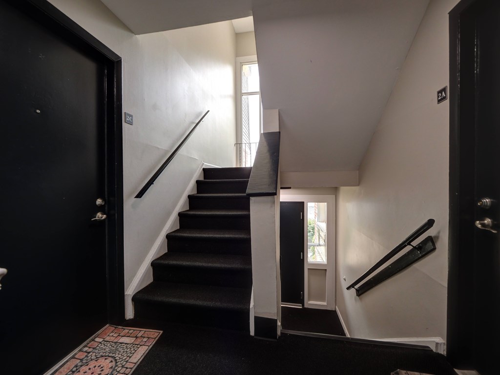A staircase with a black carpeted runner and white risers.