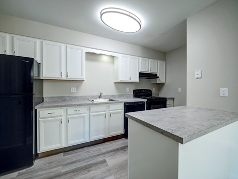 A kitchen with white cabinets and a black fridge.