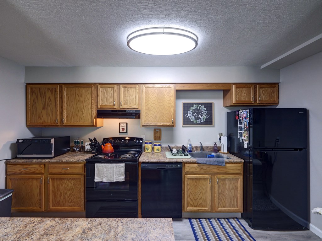Kitchen with black appliances and wooden cabinets at Cedar Park Apartments, Troy, NY