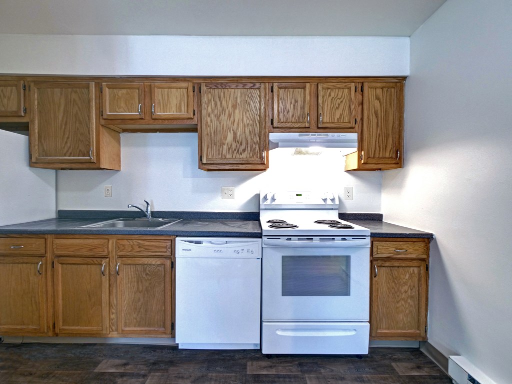 an empty kitchen with white appliances and wooden cabinets