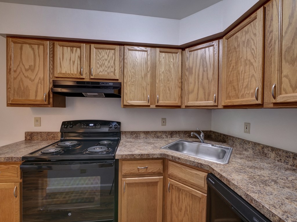an empty kitchen with wooden cabinets and a stove and sink