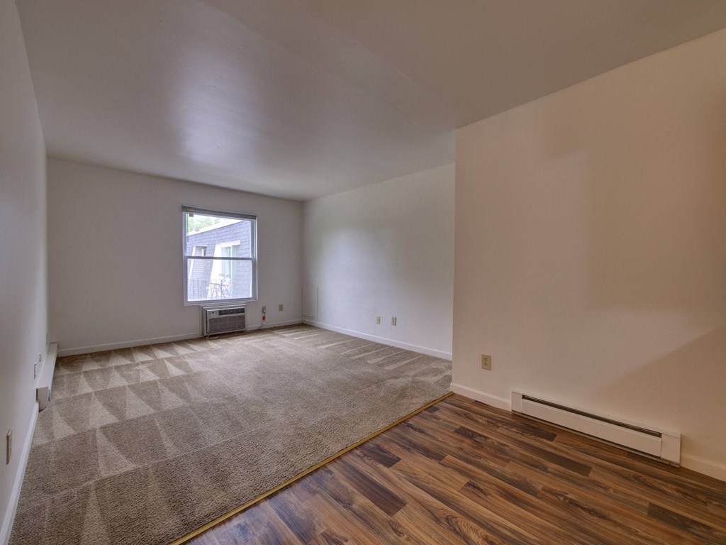 an empty living room with wood flooring and a window