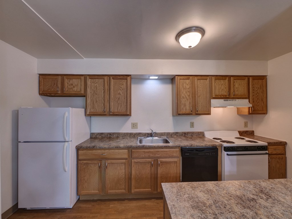 an empty kitchen with white appliances and wooden cabinets