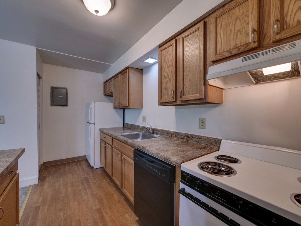 an empty kitchen with white appliances and wood cabinets