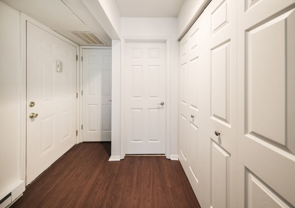a hallway with white closets and doors and a wood floor