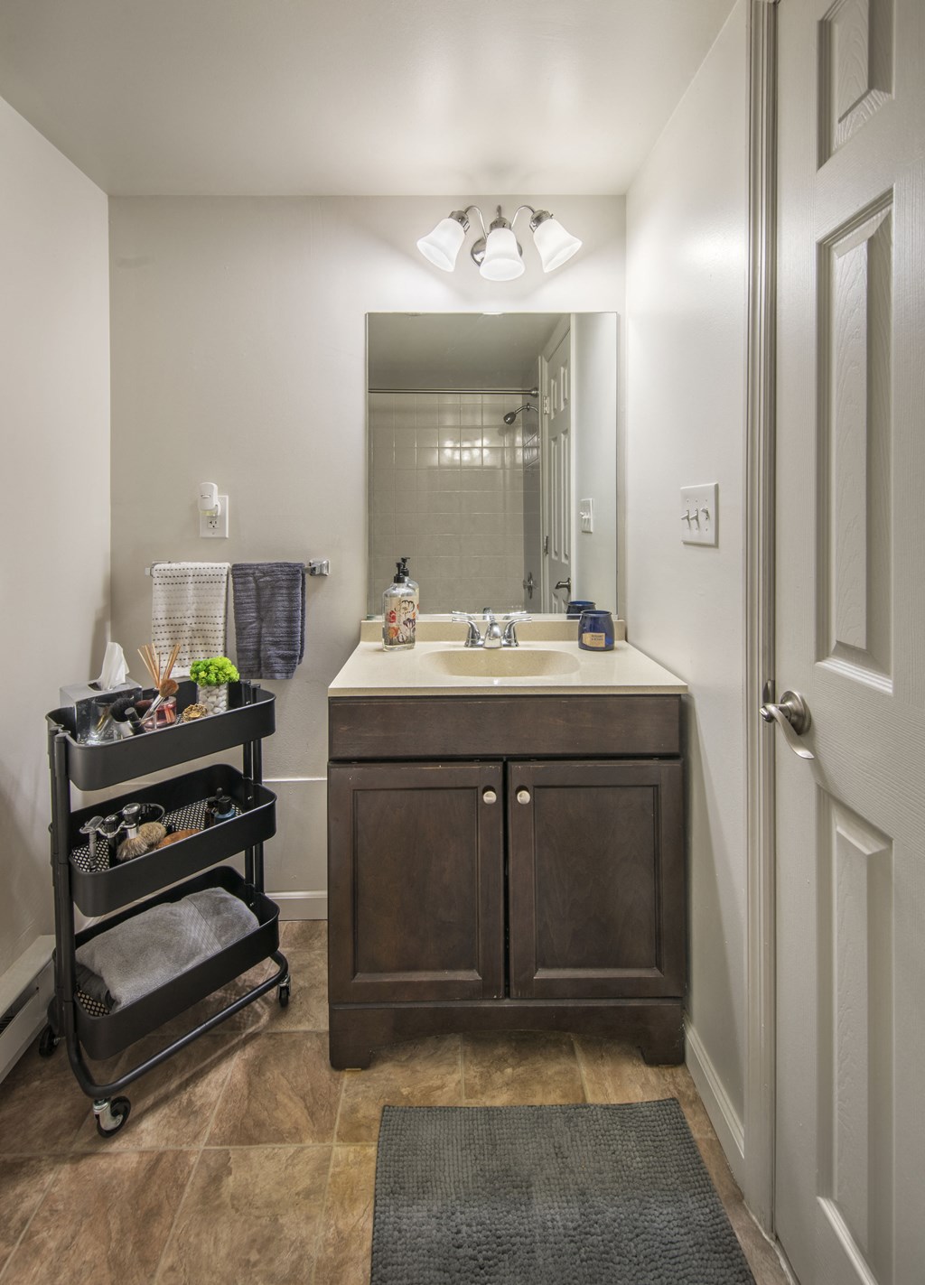 a bathroom with a sink and a mirror and a rolling cart