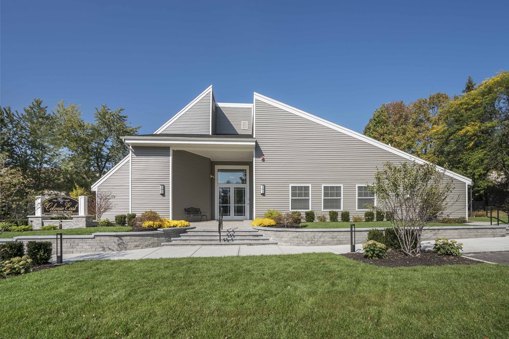 the front of a gray house with a lawn and a driveway