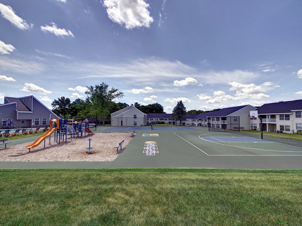 a basketball court with a playground in front of some houses