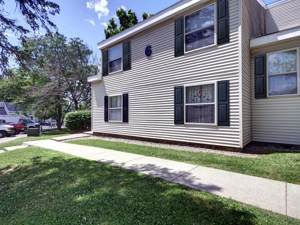 the side of a house with a sidewalk and grass