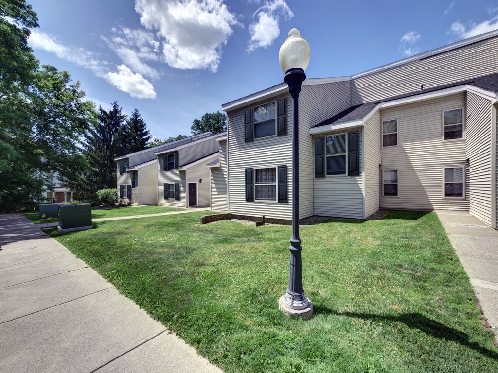 a lamp post in the grass in front of a house