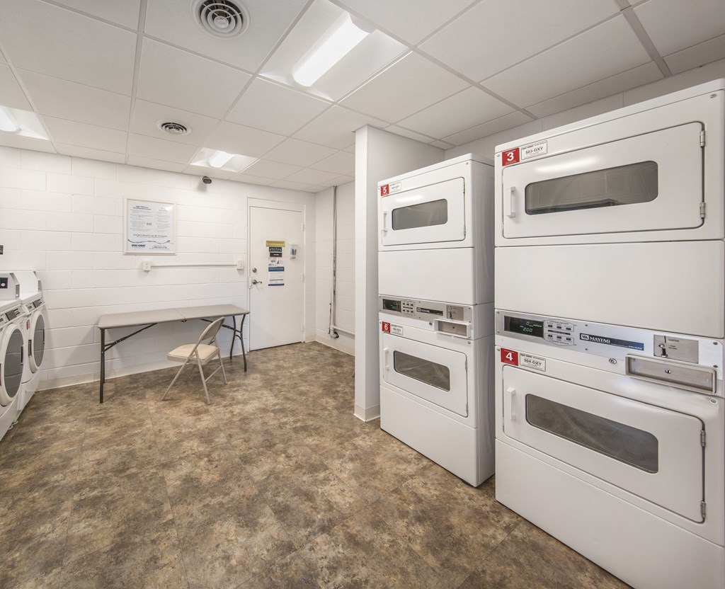 a room filled with white microwaves and a table with a chair