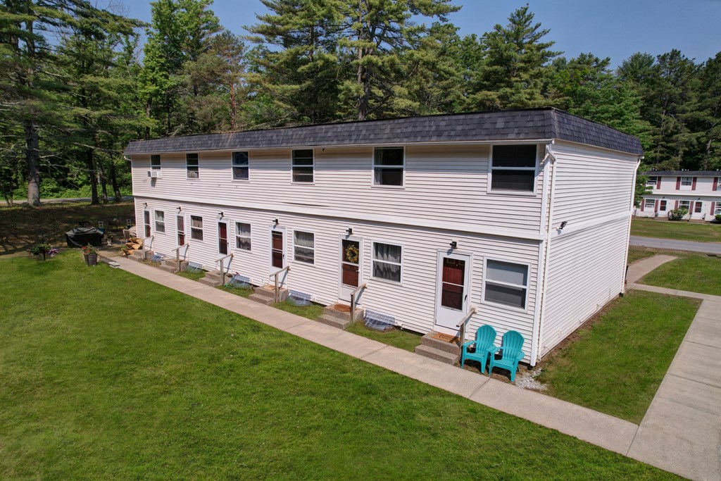 A white house with a black roof and a green lawn chair in front.