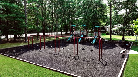 A playground with a red swing set and a green slide.