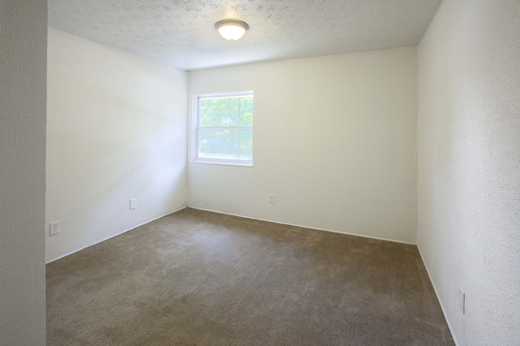 an empty room with carpet and a window