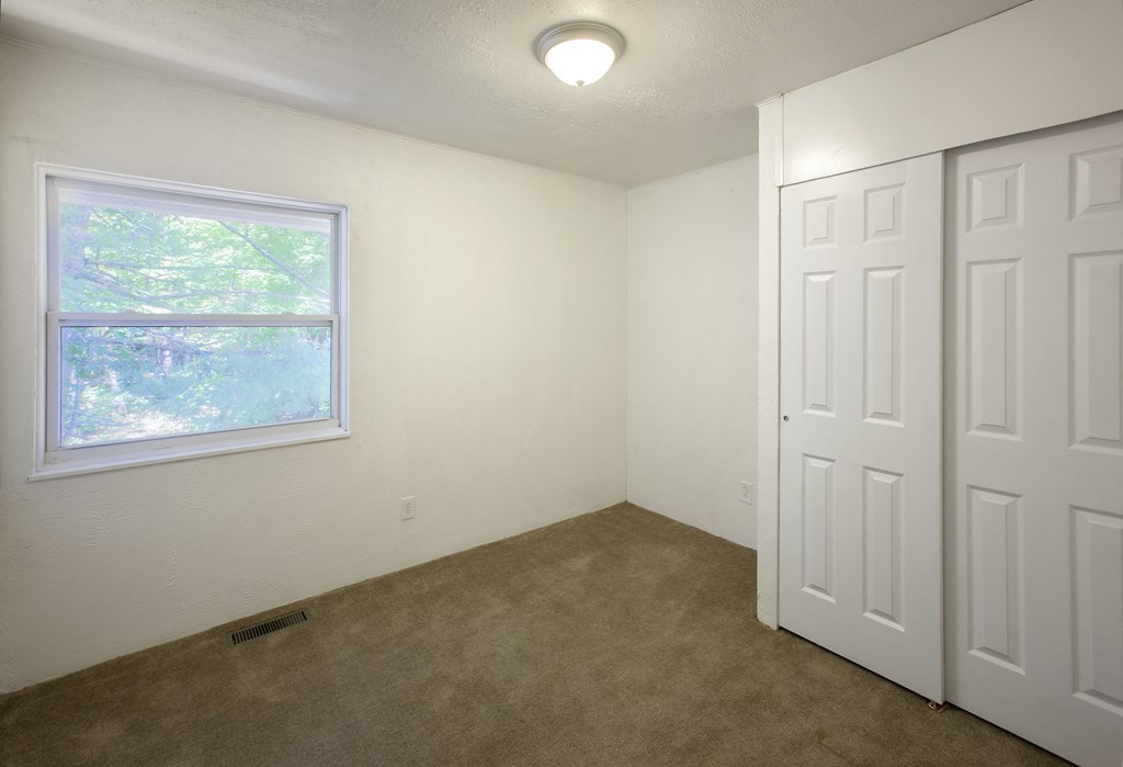 an empty room with a window and two doors