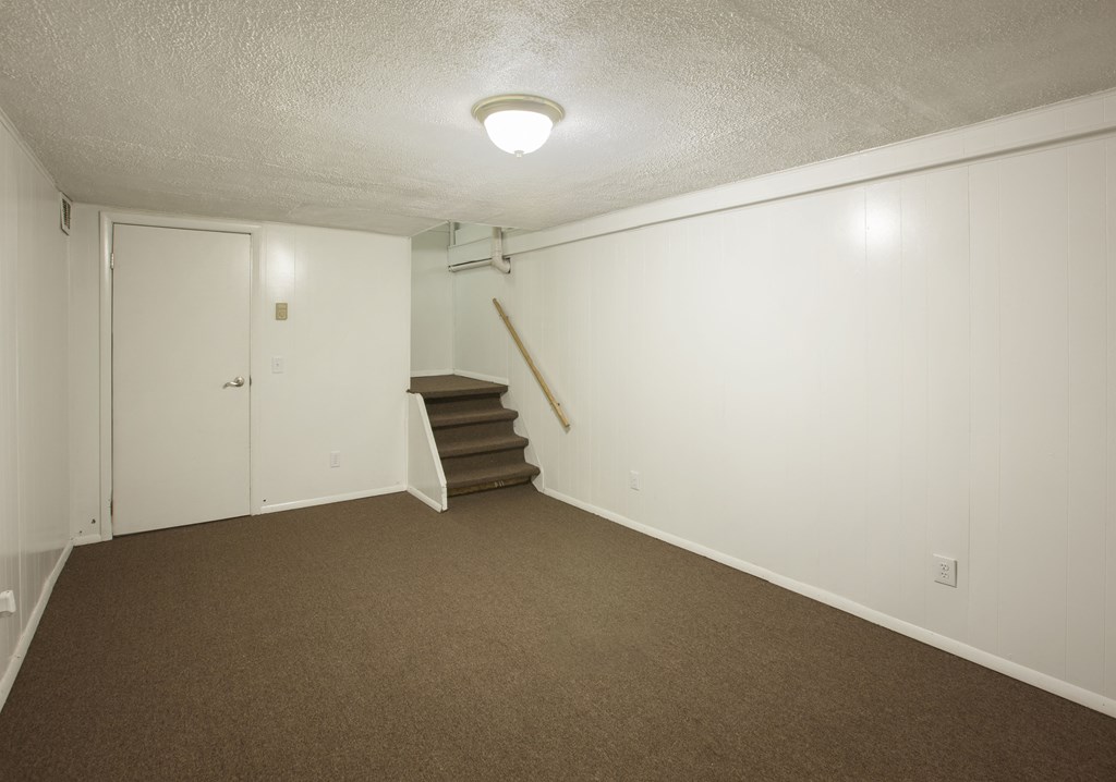 an empty living room with carpeted stairs and white walls