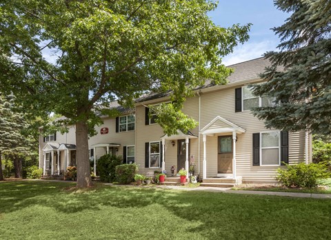 the front of a house with a lawn and trees