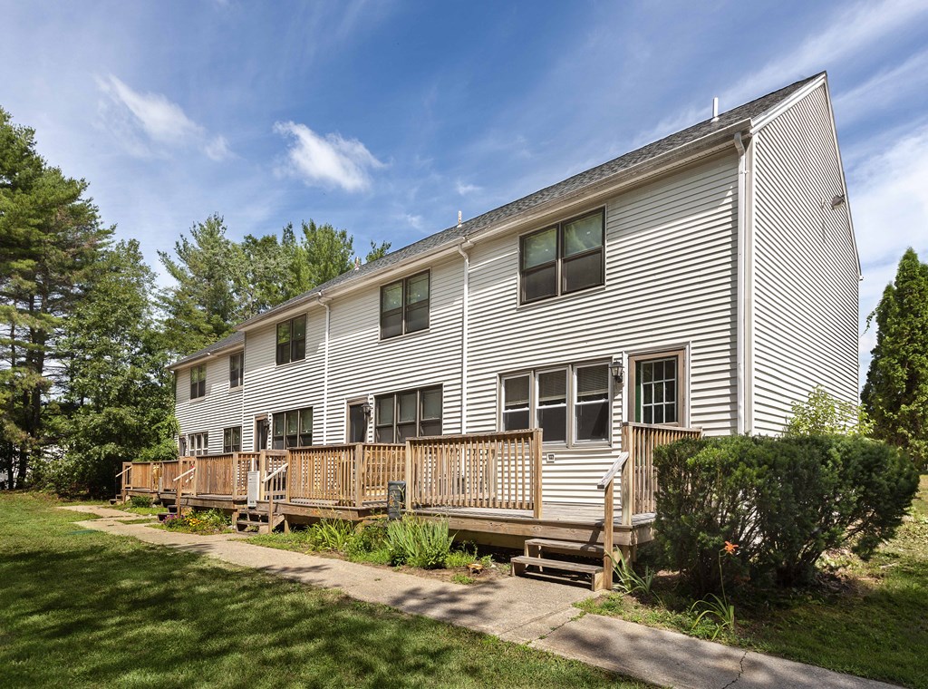 the back of a white house with a wooden deck