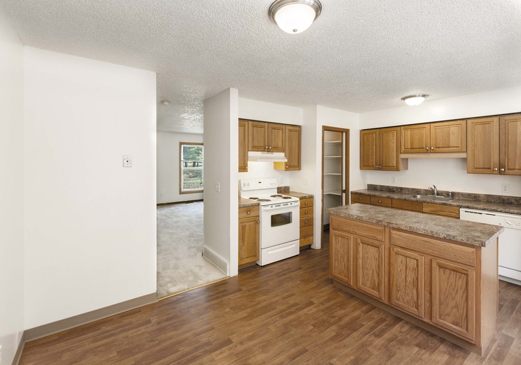 an empty kitchen with wooden cabinets and white appliances