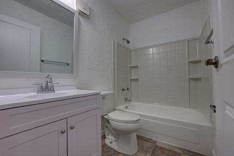 A white bathroom with a toilet, sink, and bathtub.