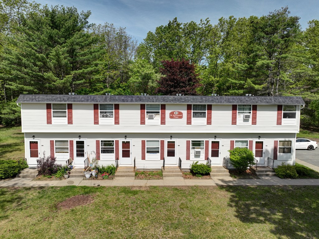 the front of a white house with red shutters and a lawn and trees