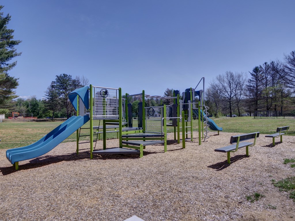 a playground with slides and benches in a park