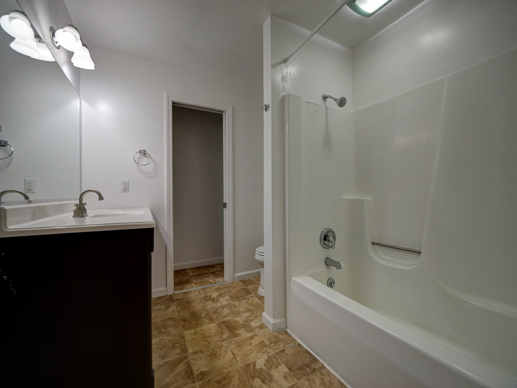 A bathroom with a sink, mirror, and bathtub.