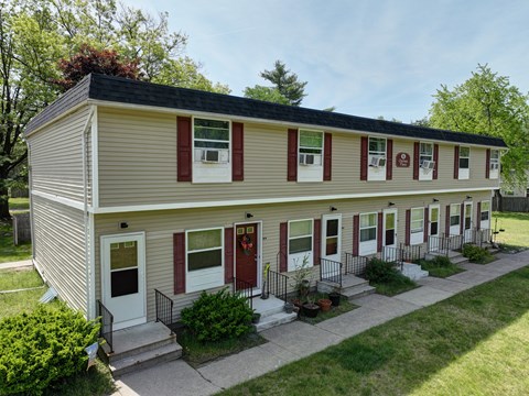 the front of a yellow house with red shutters and a sidewalk