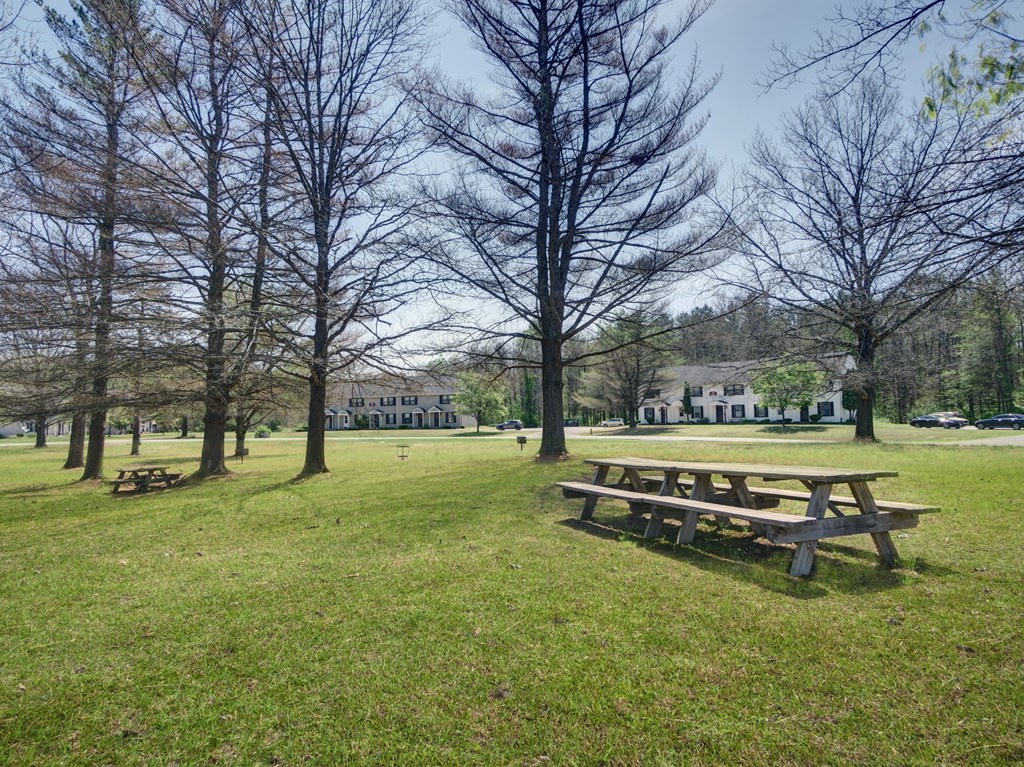 a picnic table in a park with a building in the background