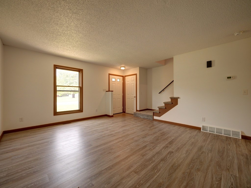 A room with wooden floors and a staircase leading to another room.