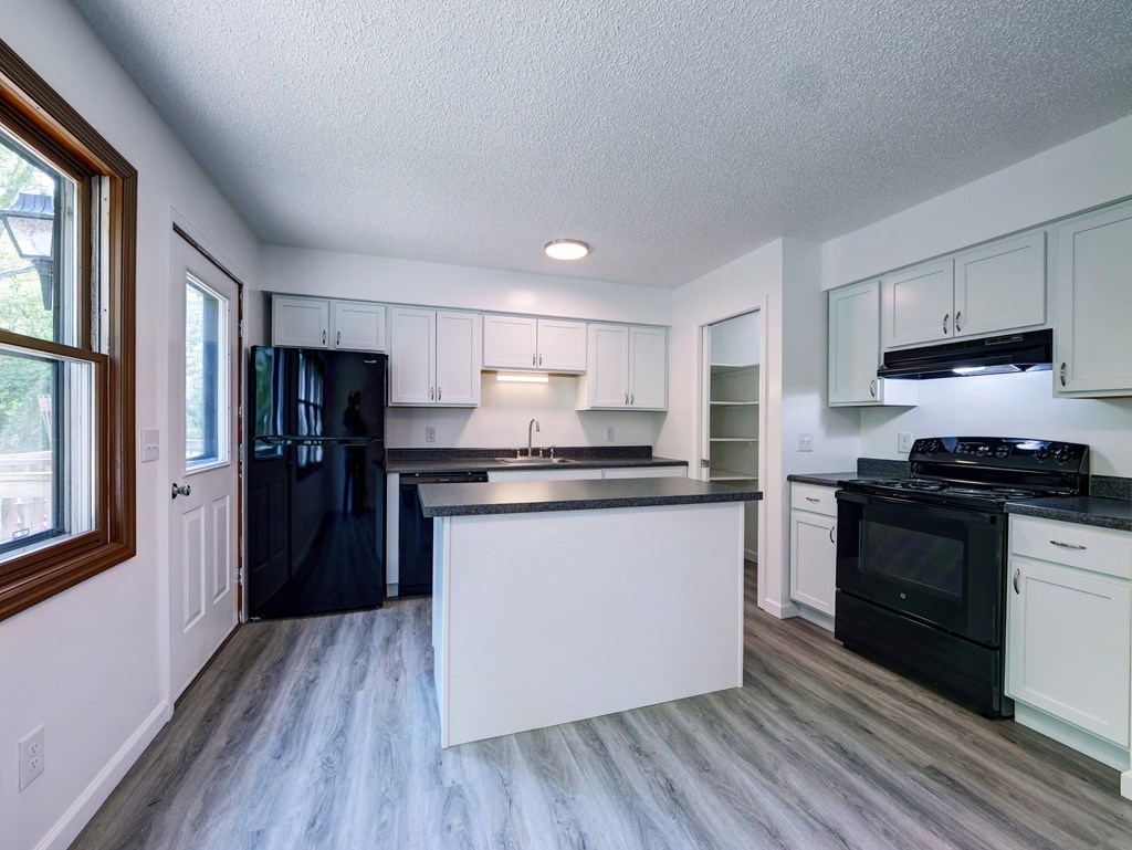 an empty kitchen with black appliances and white cabinets