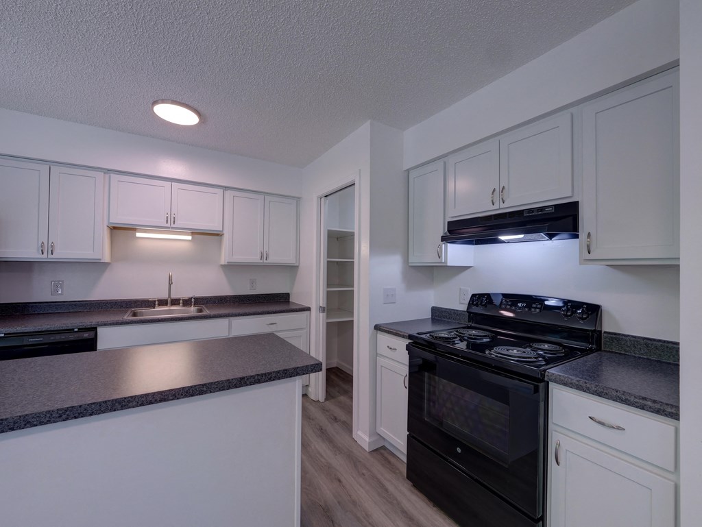 an empty kitchen with white cabinets and black appliances