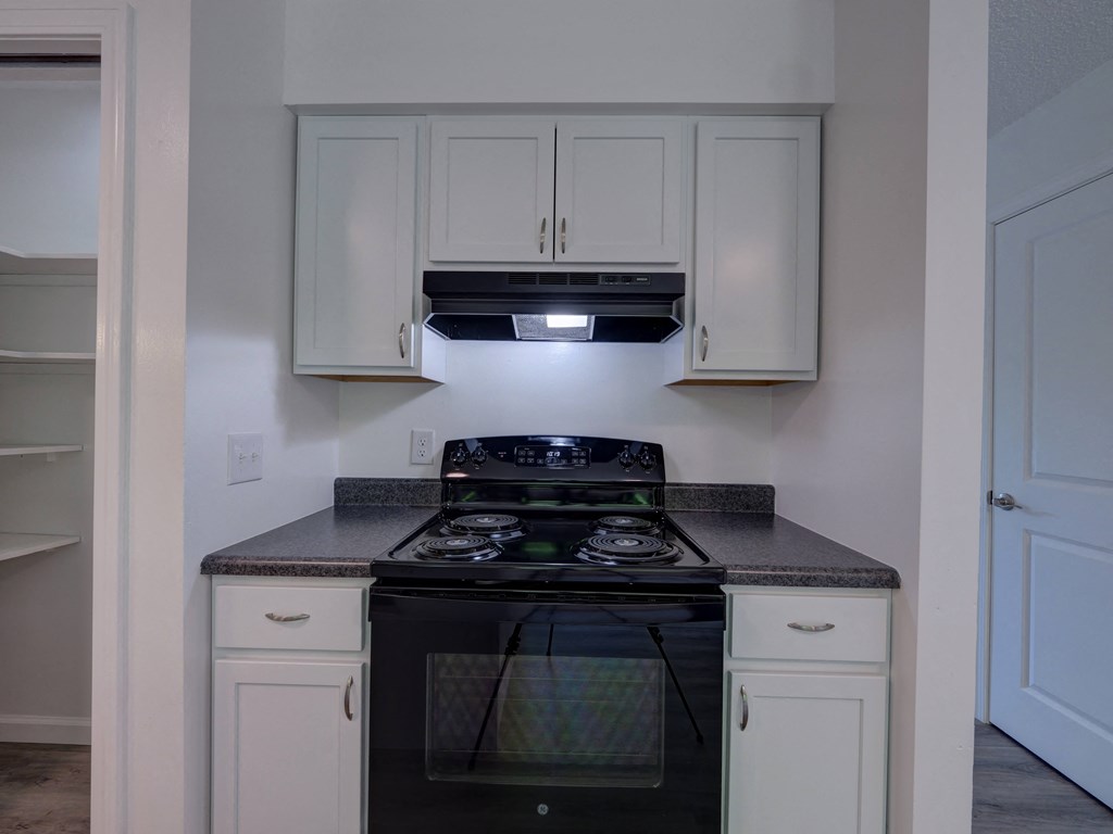 an empty kitchen with white cabinets and a black stove and oven