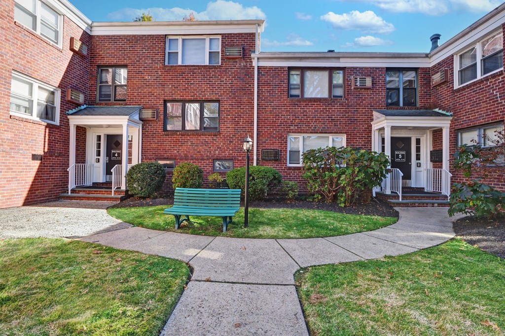 A red brick building with a green bench in front.