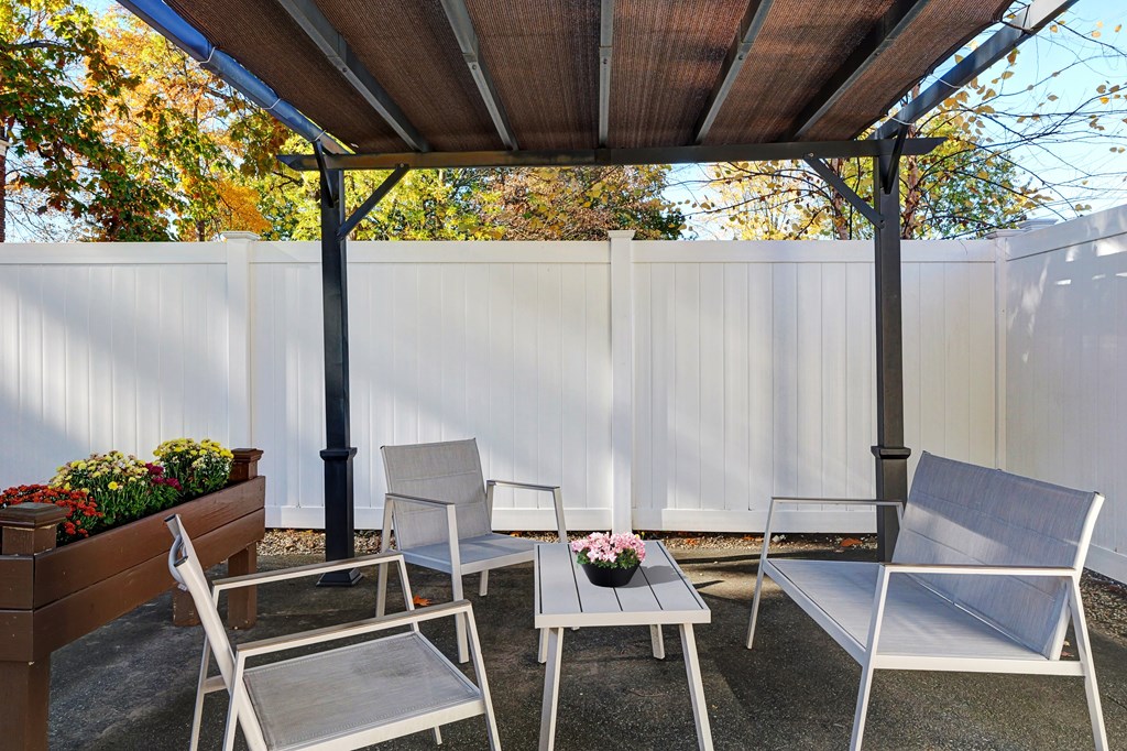 A patio with a white fence and a wooden table with chairs.