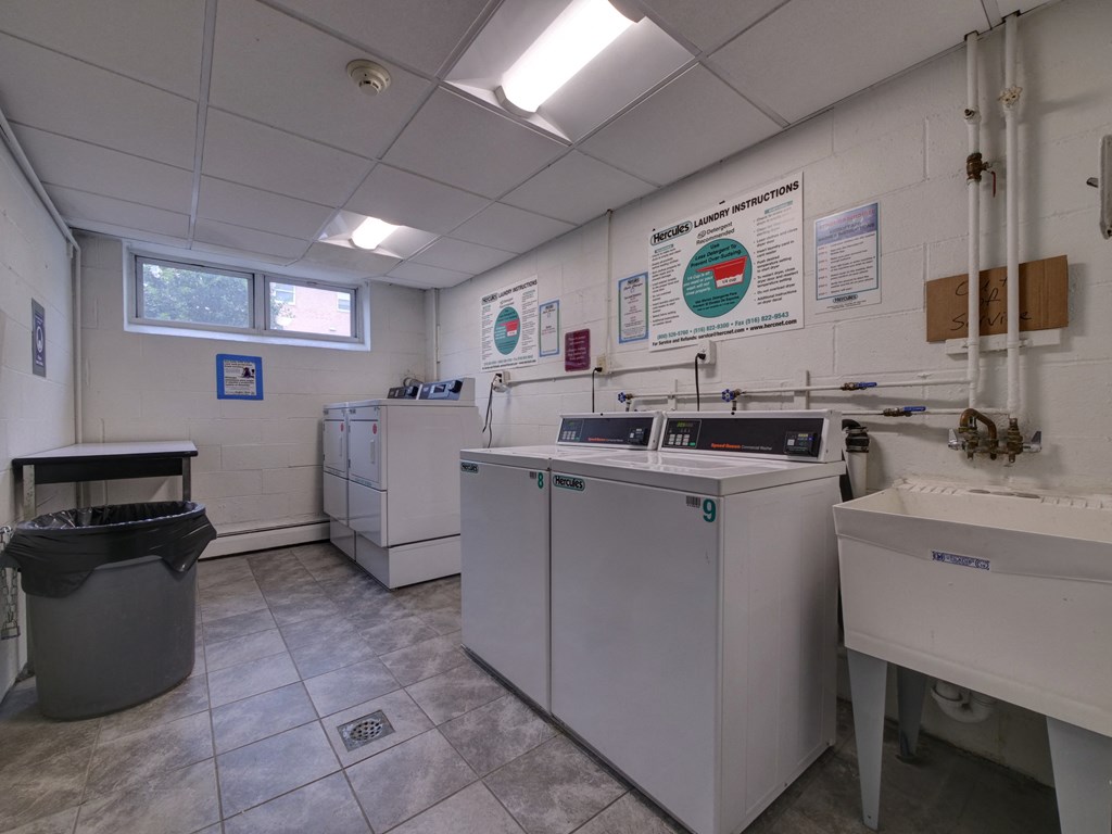 a laundry room with washing machines and sinks and a trash can