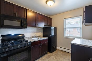A kitchen with dark wood cabinets and black appliances.