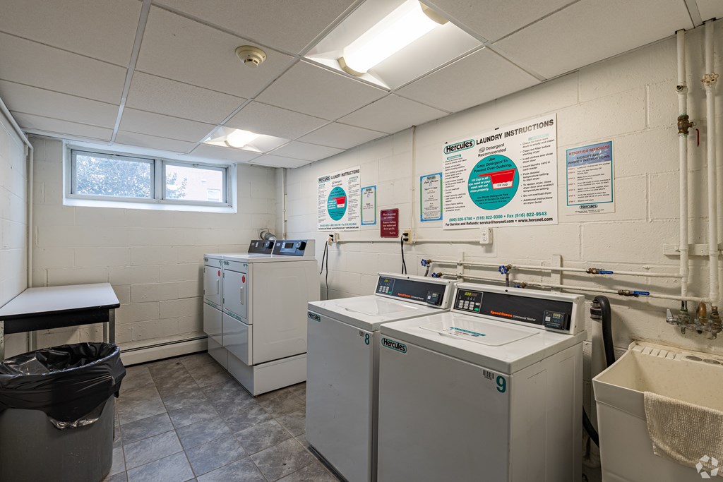 A laundry room with washers and dryers and instructions on the wall.