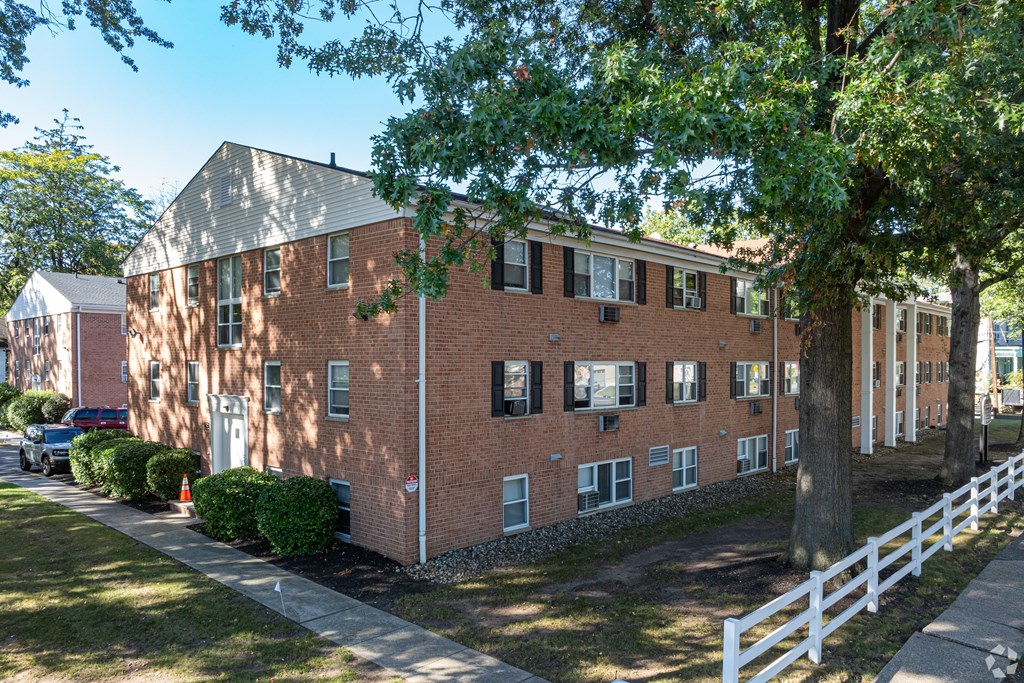 A red brick building with a white fence in front.