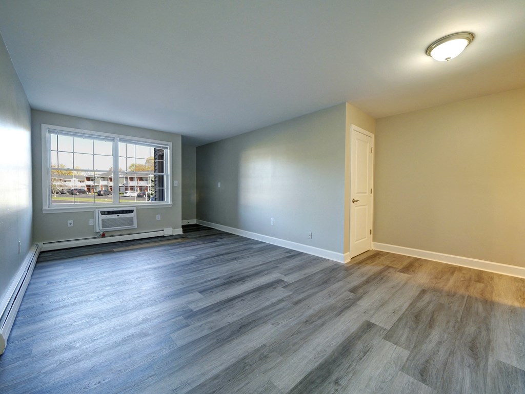 A room with a window overlooking a parking lot.