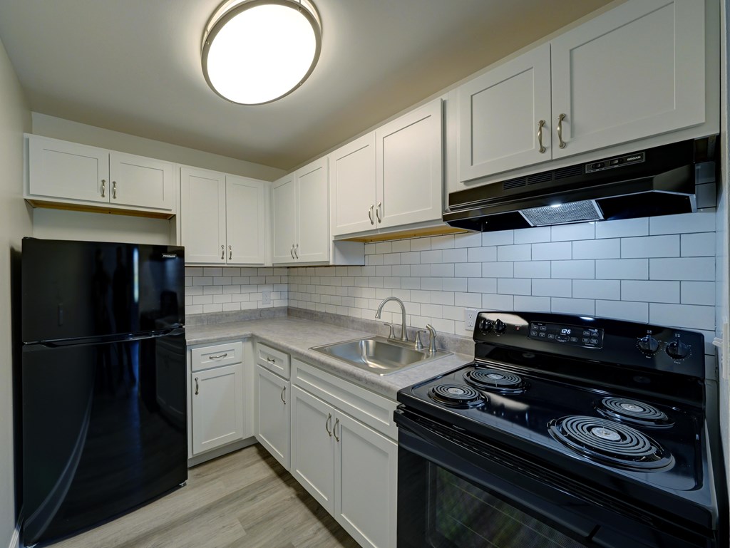 A kitchen with black appliances and white cabinets.