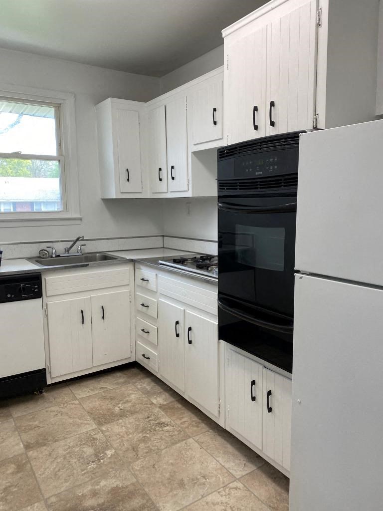 a kitchen with white cabinets and black appliances