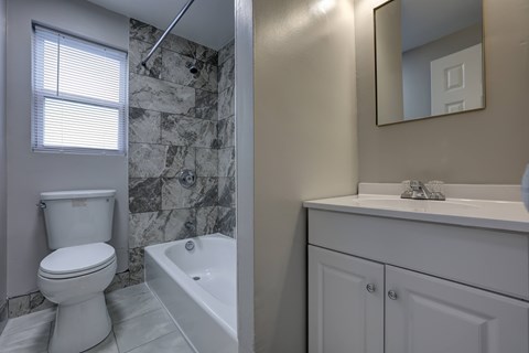 A white toilet sits next to a white bathtub in a bathroom.