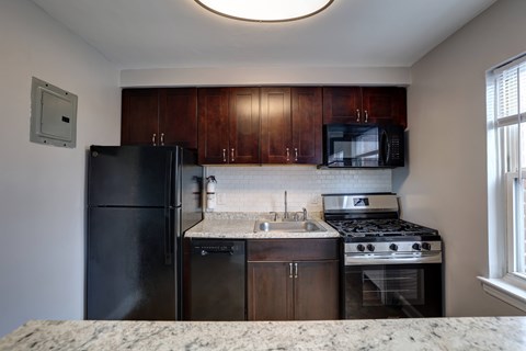 A kitchen with black appliances and brown cabinets.