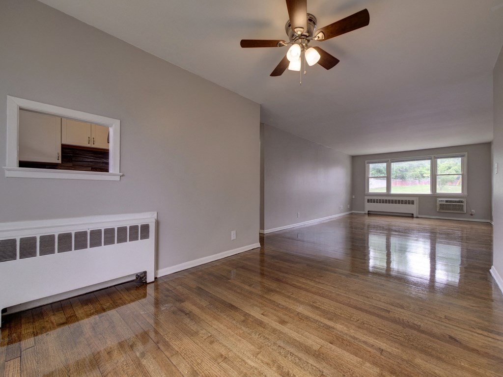 an empty living room with a ceiling fan and a window
