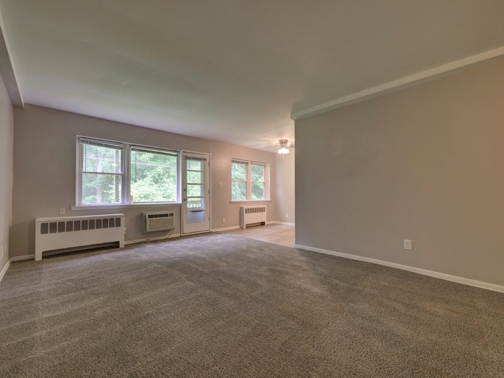 an empty living room with a radiator and a window