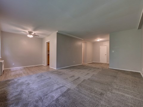 an empty living room with gray walls and a ceiling fan