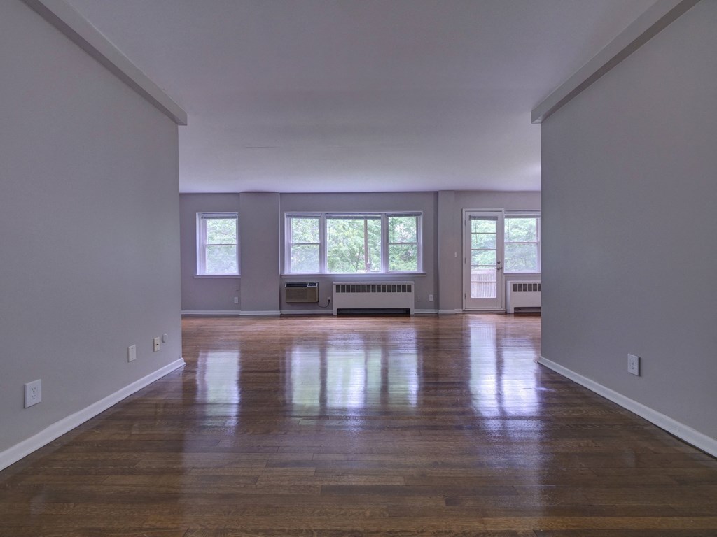 an empty living room with a hard wood floor and windows