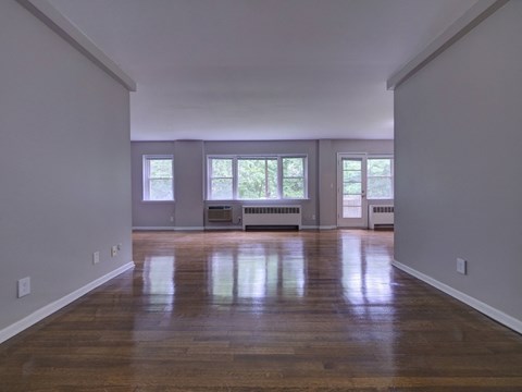 an empty living room with a hard wood floor and windows